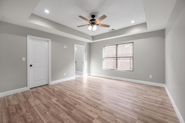 spare room featuring ceiling fan, a raised ceiling, and light hardwood / wood-style flooring