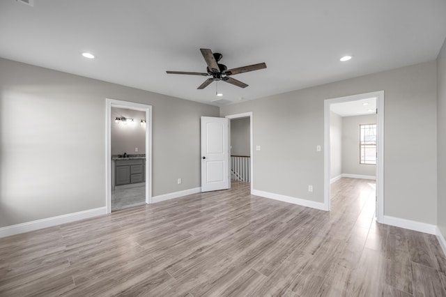 unfurnished bedroom featuring ceiling fan, ensuite bath, and light hardwood / wood-style floors