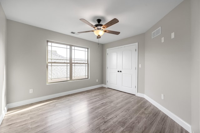 unfurnished bedroom featuring ceiling fan, light hardwood / wood-style floors, and a closet