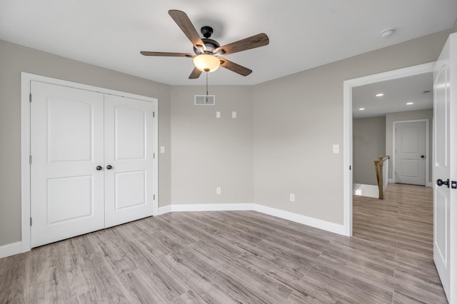 unfurnished bedroom featuring ceiling fan, a closet, and light wood-type flooring