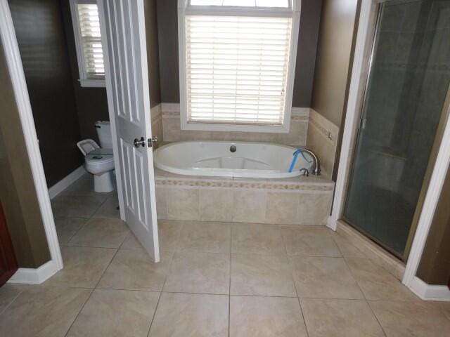 bathroom with tile patterned floors, toilet, and separate shower and tub