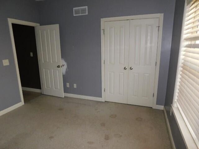 unfurnished bedroom featuring light colored carpet and a closet