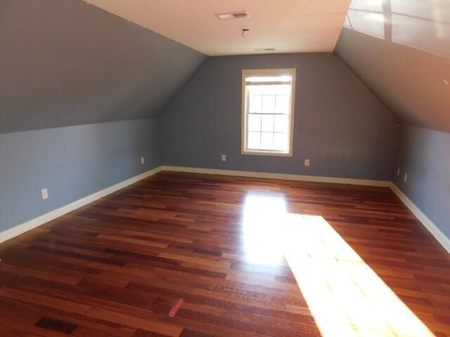 additional living space with vaulted ceiling and dark hardwood / wood-style flooring