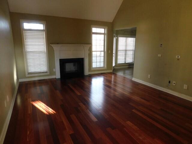 unfurnished living room featuring lofted ceiling and dark hardwood / wood-style floors