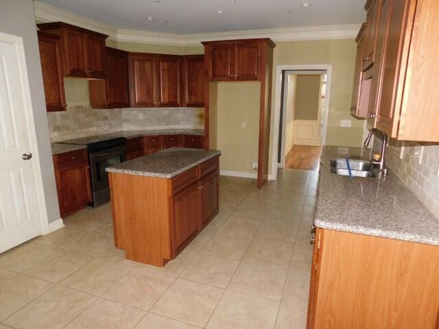 kitchen with electric stove, sink, crown molding, a kitchen island, and decorative backsplash