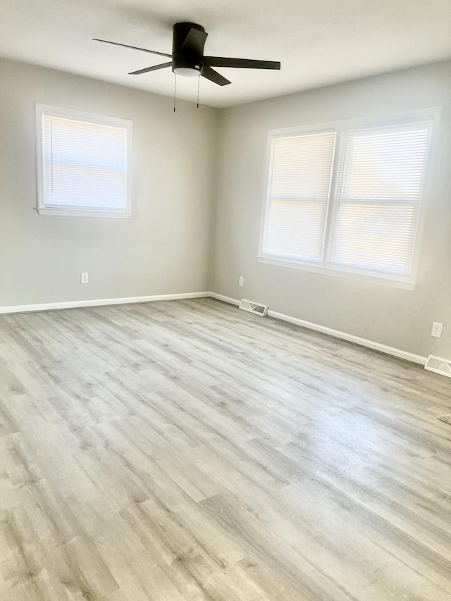 empty room with ceiling fan, plenty of natural light, and light hardwood / wood-style floors