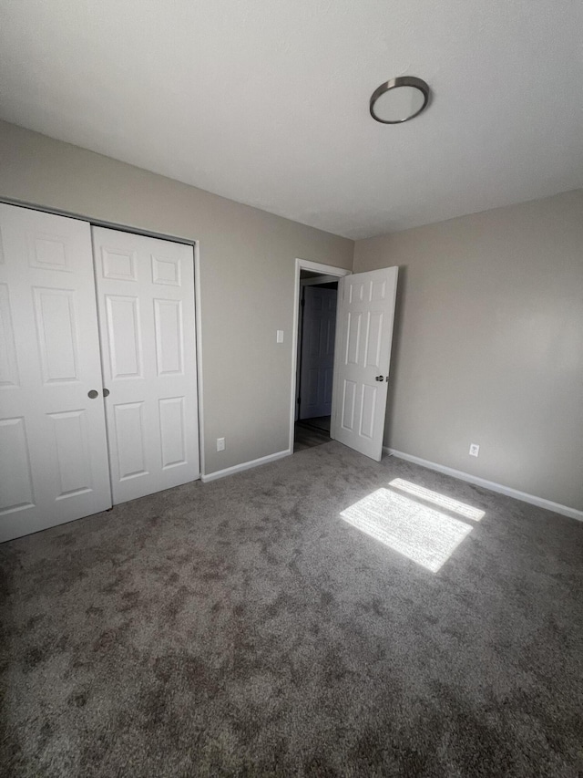 unfurnished bedroom featuring a closet and dark colored carpet