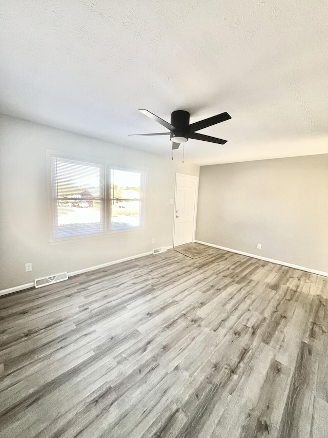 empty room with ceiling fan, a textured ceiling, and light wood-type flooring