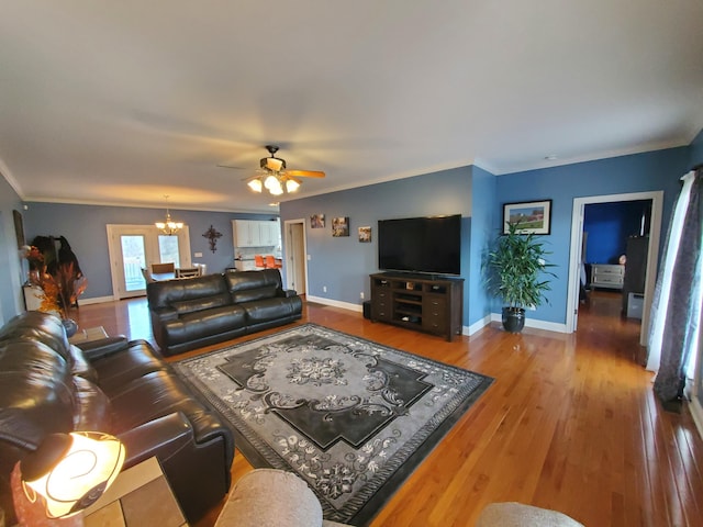 living room featuring hardwood / wood-style floors, ceiling fan with notable chandelier, and ornamental molding