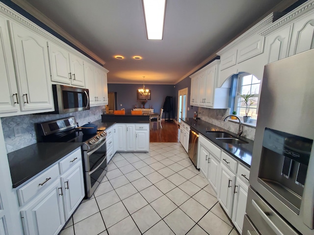 kitchen with sink, white cabinetry, stainless steel appliances, a notable chandelier, and kitchen peninsula