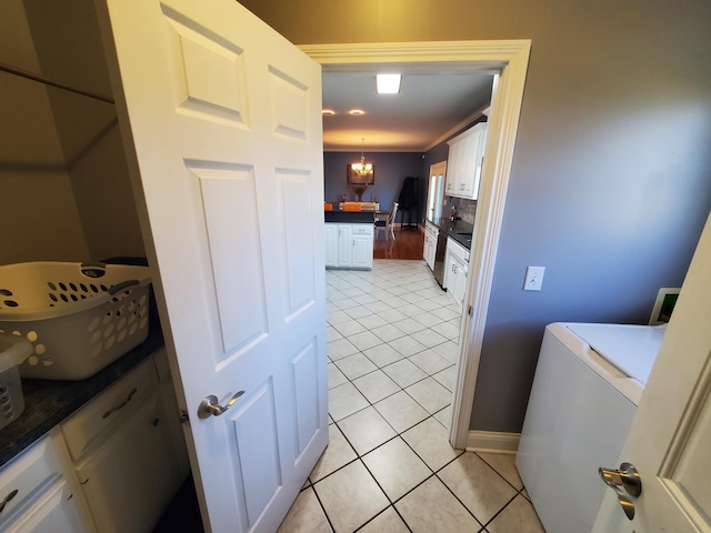 washroom featuring light tile patterned floors, washer / dryer, cabinets, and a chandelier