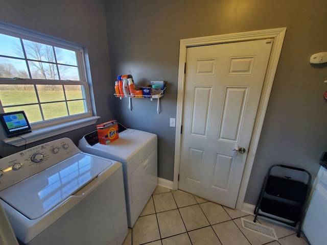 clothes washing area featuring light tile patterned floors and washer and clothes dryer