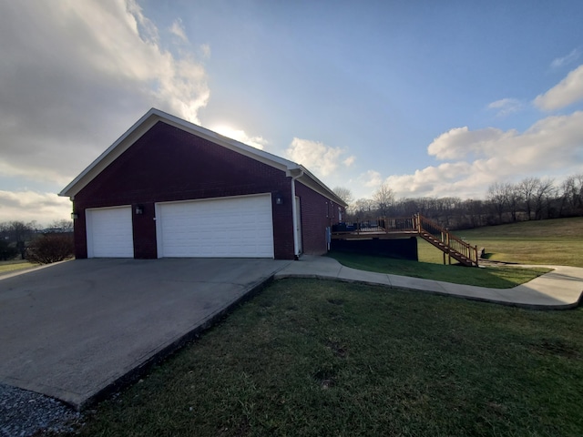 view of side of property featuring a garage and a lawn