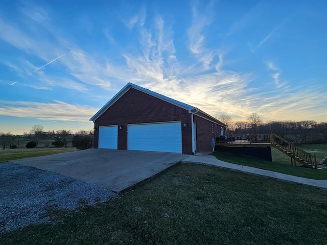 garage at dusk featuring a lawn