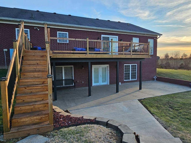 back house at dusk featuring french doors, a wooden deck, and a patio area