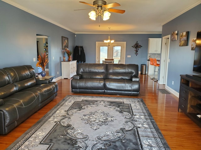 living room featuring crown molding, dark wood-type flooring, and ceiling fan with notable chandelier