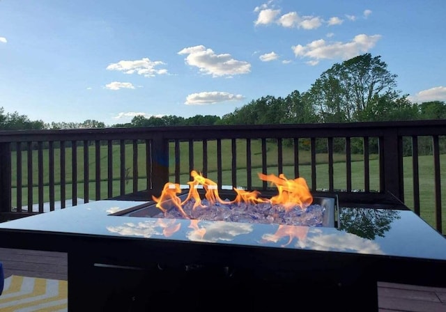 wooden terrace featuring a fire pit and a lawn