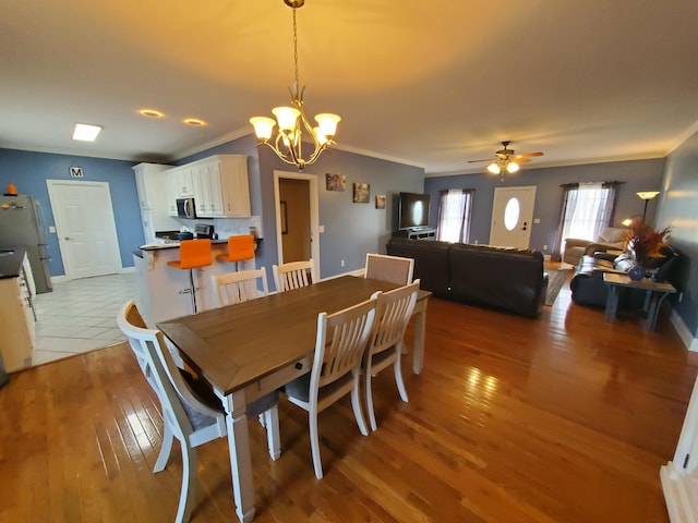 dining room with ceiling fan with notable chandelier, ornamental molding, and light hardwood / wood-style floors