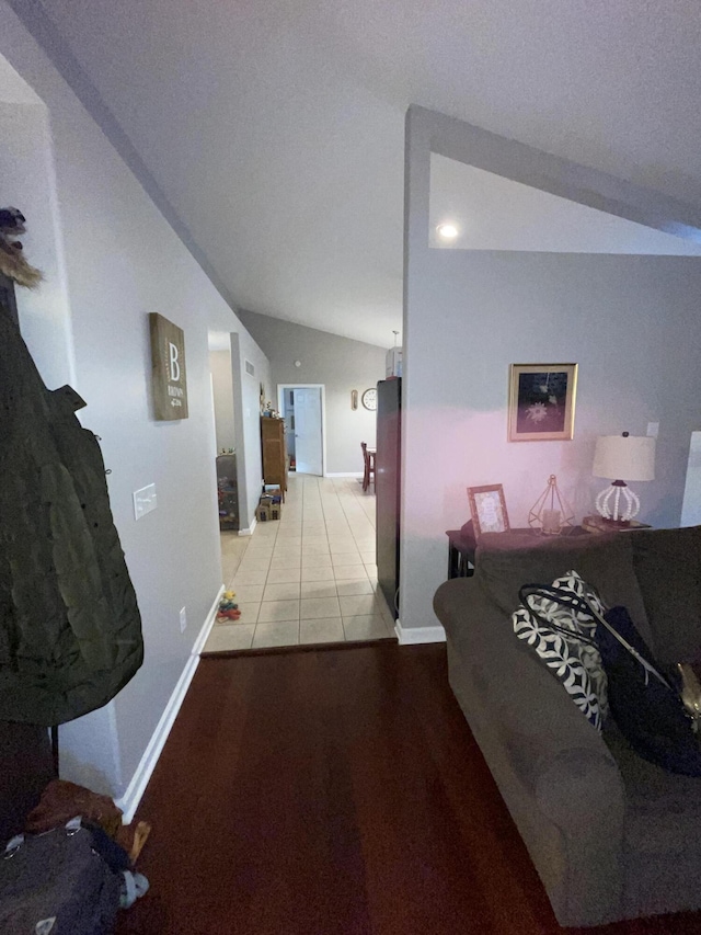 hallway featuring lofted ceiling, light tile patterned flooring, and baseboards