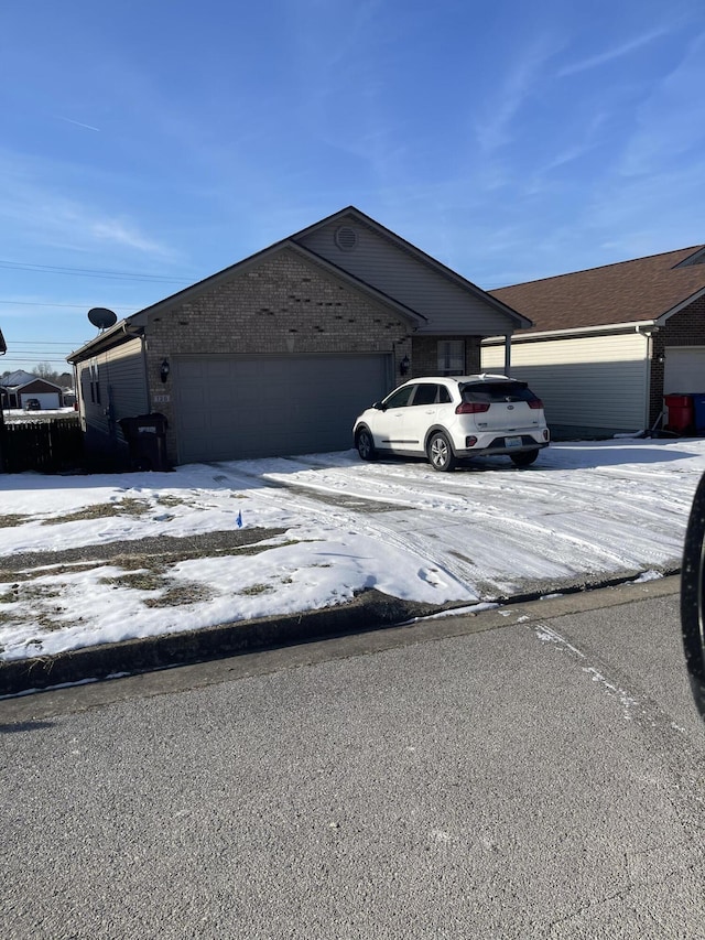 view of snowy exterior with brick siding and an attached garage