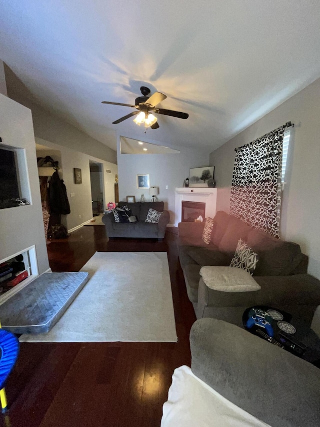 living room featuring ceiling fan, a fireplace, vaulted ceiling, and wood finished floors