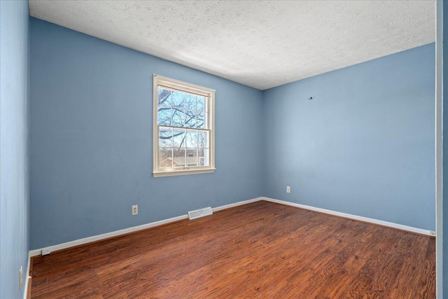 spare room featuring hardwood / wood-style floors and a textured ceiling