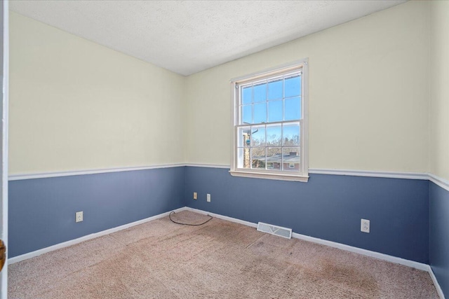 carpeted empty room featuring a textured ceiling