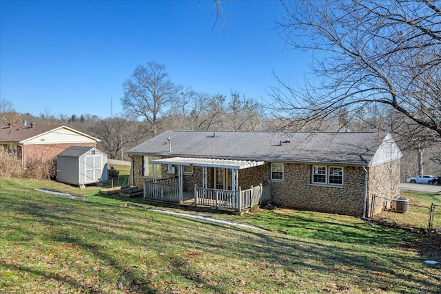 rear view of property with a wooden deck, a shed, central AC, and a lawn