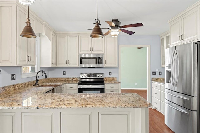 kitchen featuring light stone counters, sink, decorative light fixtures, and stainless steel appliances