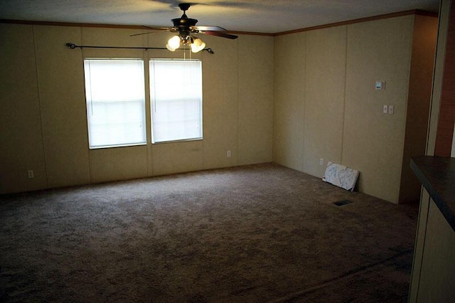 carpeted spare room featuring crown molding and ceiling fan