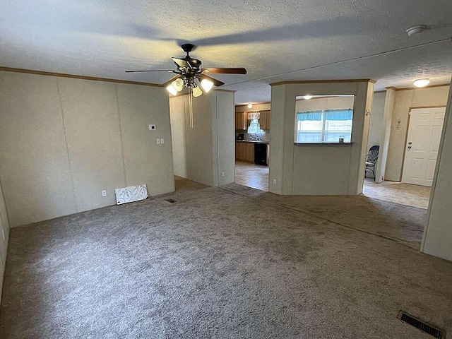 carpeted empty room featuring ceiling fan, ornamental molding, and a textured ceiling