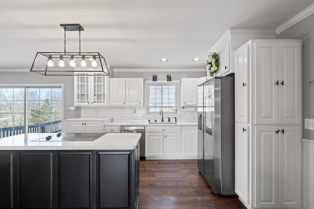 kitchen featuring sink, a center island, hanging light fixtures, stainless steel appliances, and white cabinets