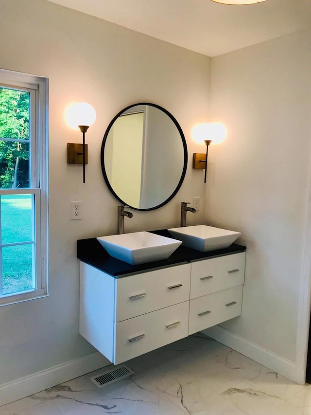 bathroom with marble finish floor, plenty of natural light, a sink, and visible vents