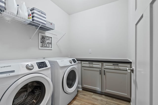 laundry area with cabinets, washing machine and dryer, and light wood-type flooring