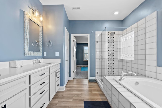 bathroom featuring hardwood / wood-style flooring, vanity, and separate shower and tub