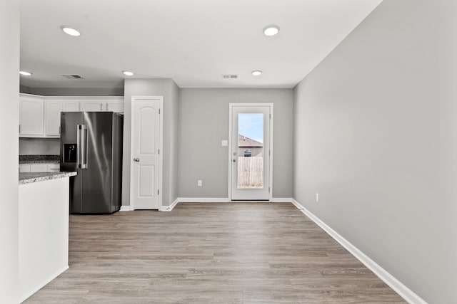 kitchen featuring light stone counters, light hardwood / wood-style flooring, high quality fridge, and white cabinets