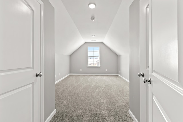 additional living space featuring vaulted ceiling and carpet flooring