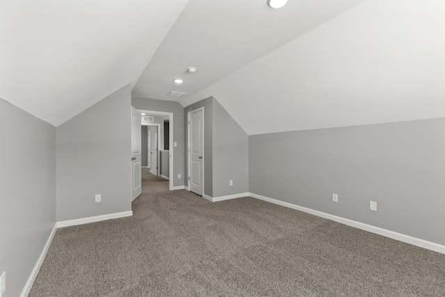 additional living space featuring vaulted ceiling and carpet flooring