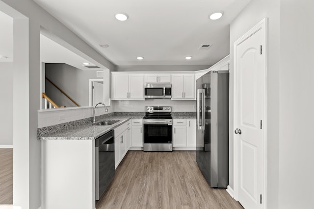 kitchen with light stone counters, sink, stainless steel appliances, and white cabinets