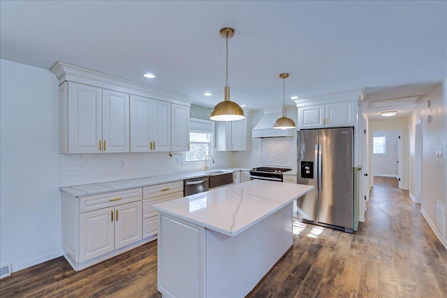 kitchen with stainless steel appliances, a center island, white cabinets, and premium range hood