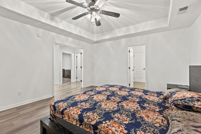 bedroom featuring ceiling fan, a tray ceiling, and hardwood / wood-style floors