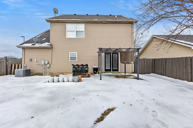 snow covered back of property featuring central AC unit and a pergola