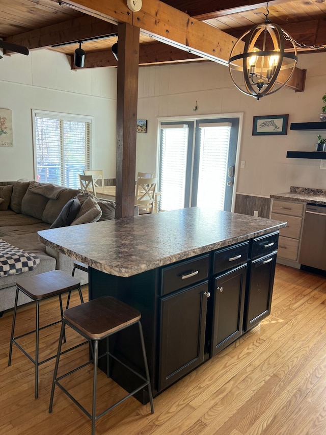 kitchen featuring stainless steel dishwasher, beam ceiling, a center island, and a breakfast bar area