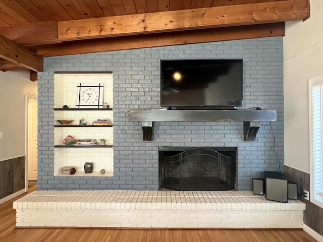 living room with hardwood / wood-style floors, a fireplace, beamed ceiling, and wood walls