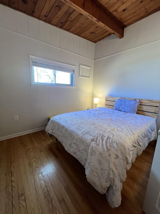 bedroom with beamed ceiling, wood ceiling, and dark hardwood / wood-style flooring