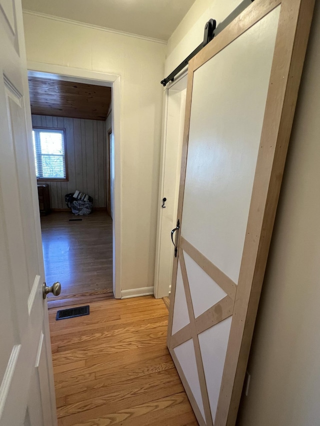 hallway with a barn door and light hardwood / wood-style flooring