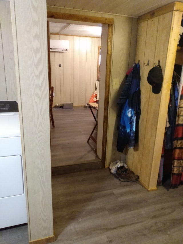 interior space featuring washer / clothes dryer, hardwood / wood-style flooring, a wall mounted air conditioner, and wood walls