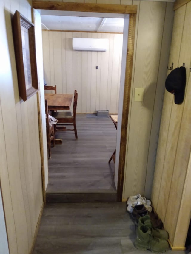 hall with dark hardwood / wood-style floors, a wall mounted AC, and wooden walls