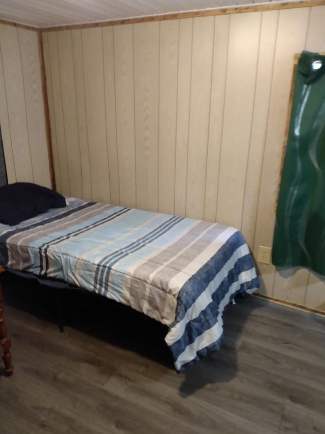 bedroom with dark hardwood / wood-style flooring and wood walls