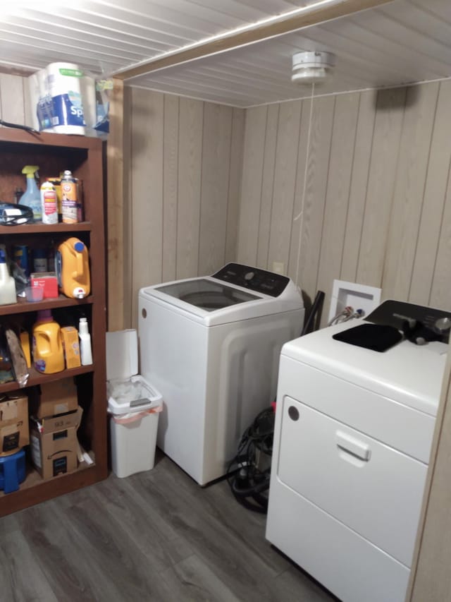 washroom with separate washer and dryer, dark hardwood / wood-style flooring, and wood walls